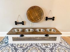 an elevated dog food station with three bowls and two bone magnets on the wall