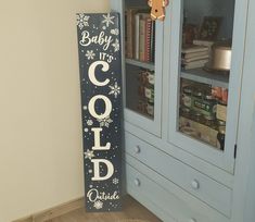 a wooden sign that says baby it's cold outside next to a bookcase