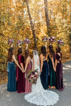 a group of women standing next to each other in front of trees with flowers on their heads