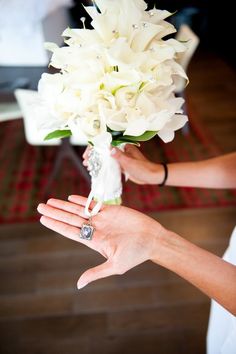 a woman holding a bouquet of white flowers in her left hand and an engagement ring on her right hand