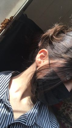 a woman with her hair pulled back and wearing a black and white striped shirt is looking at the camera