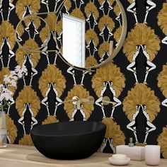 a black bowl sitting on top of a wooden table next to a mirror and vase