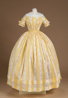 Litchfield Historical Society Dress of printed cotton; repeating design of solid yellow vertical stripe and white stripe with purple and red flowers; off the shoulder neckline; short sleeves trimmed with two rows of pleats; front of dress gathered at angles from a wide corded waist band; plain back fastened with hooks and eyes; full skirt (bell shaped) gathered at waist and has two hems 1850 Dress, Cotton Stripe Dresses, Victorian Clothing