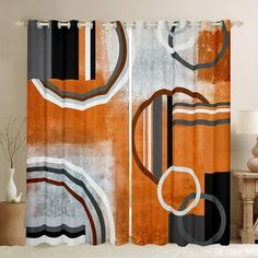 an orange and black curtain hanging on a wall next to a table with a lamp