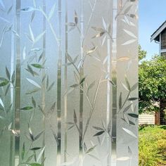 two glass panels with leaves on them in front of a house