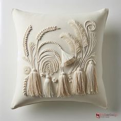 an embroidered pillow with tassels on it