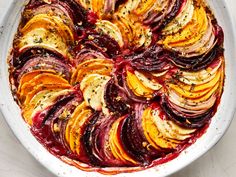 a dish with beets, onions and herbs in it on a white table top