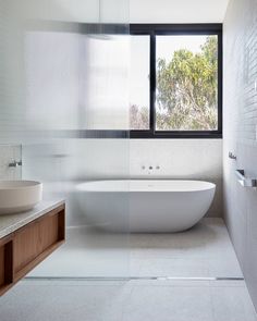 a white bath tub sitting under a window next to a sink