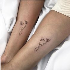 two people with matching tattoos on their legs, one is holding the other's hand