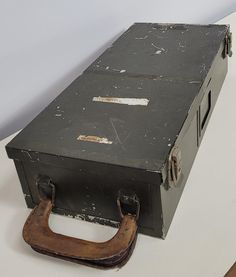 an old metal box sitting on top of a white table next to a wooden shoe