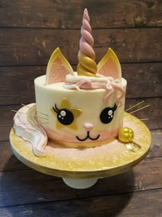 a cake with a cat face and unicorn horn on it's head is sitting on a gold plate