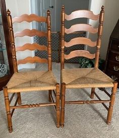 two wooden chairs sitting next to each other in front of a mirror on the floor