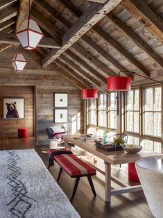 a room with wooden walls and flooring has red lamps hanging from the ceiling