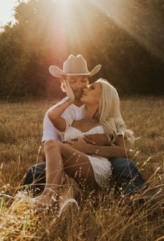 a man and woman sitting in the grass kissing