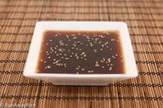 a square white plate filled with sauce on top of a woven tablecloth covered place mat