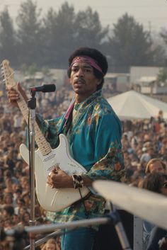 an image of a man that is playing guitar in front of a large group of people