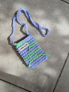 a crocheted cell phone case sitting on top of a cement floor next to a string