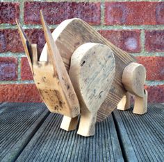 a wooden toy that looks like an elephant on a table next to a brick wall