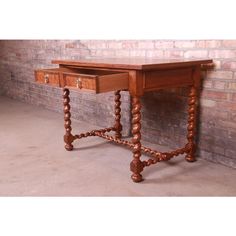 an old wooden desk with two drawers on it's legs, against a brick wall