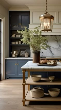 a kitchen with blue cabinets and marble counter tops, an island in the foreground