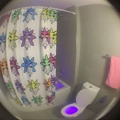 a bathroom with a toilet, shower curtain and colorful stars on the curtains is seen through a fish eye lens