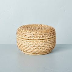 a woven basket sitting on top of a white table next to a wall and floor