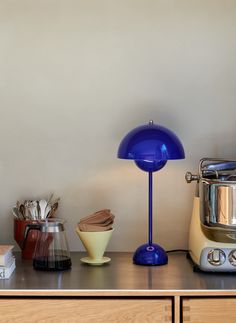 a blue lamp sitting on top of a counter next to a blender and mixer