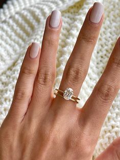 a woman's hand with a ring on it and a white sweater in the background