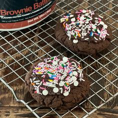 two chocolate cookies with sprinkles on a cooling rack next to a can of brownie batter