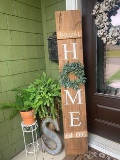 a wooden sign sitting next to a potted plant on top of a door sill