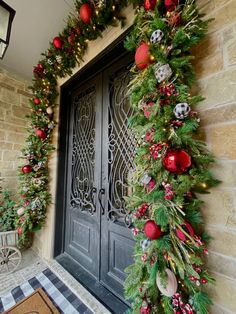 a christmas wreath on the front door of a house with ornaments hanging from it's sides