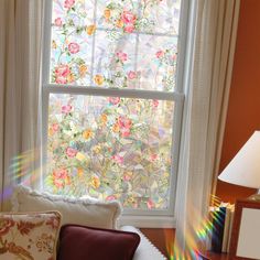 a living room with a large window covered in stained glass flowers and white drapes