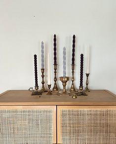 an assortment of candles on top of a dresser