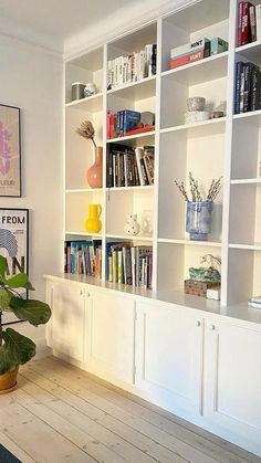 a living room filled with lots of white bookshelves