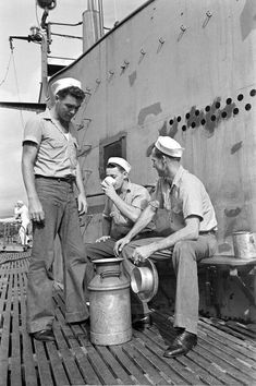 two men are sitting on the deck of a ship and one man is holding a bucket