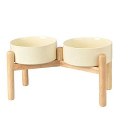 two white bowls sitting on top of wooden legs