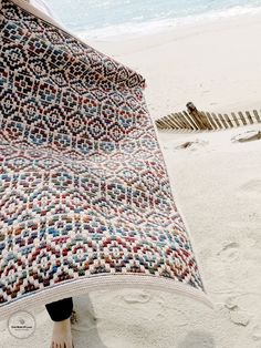 a person standing on the beach under a blanket