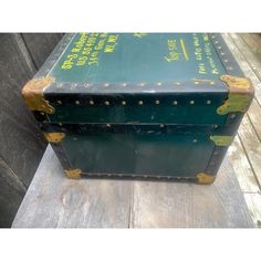 an old green suitcase sitting on top of a wooden floor