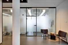 an office with glass walls and two chairs