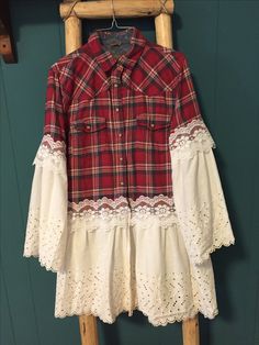 a red and white plaid shirt hanging on a clothes hanger with lace trims