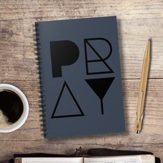 an open book sitting on top of a wooden table next to a cup of coffee