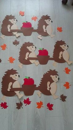 hedgehogs with apples and leaves cut out on the floor in front of them