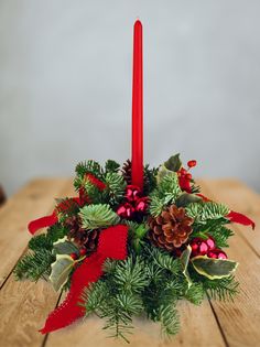 a christmas centerpiece with pine cones and red ribbon