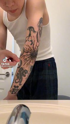 a man with a dragon tattoo on his arm is looking at the camera while standing in front of a bathroom sink