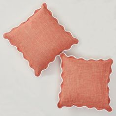 two orange pillows with scalloped edges on a white surface, one in the shape of a pillow