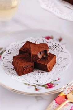 three pieces of chocolate fudge cake on a white plate next to a glass of wine