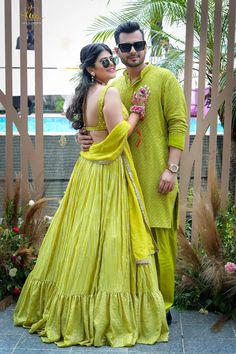 a man and woman dressed in yellow standing next to each other with their arms around each other