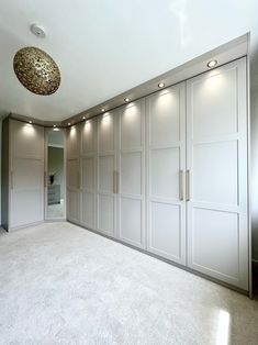 an empty room with white cupboards and lights on the ceiling is pictured in this image