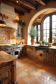 a large kitchen with an arched window and tile flooring on the walls, along with potted plants