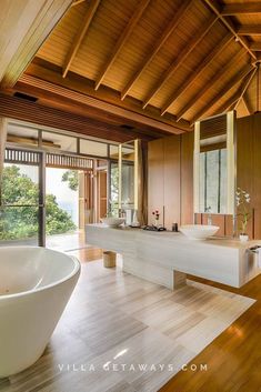 a large white bath tub sitting inside of a bathroom next to a wooden floored wall